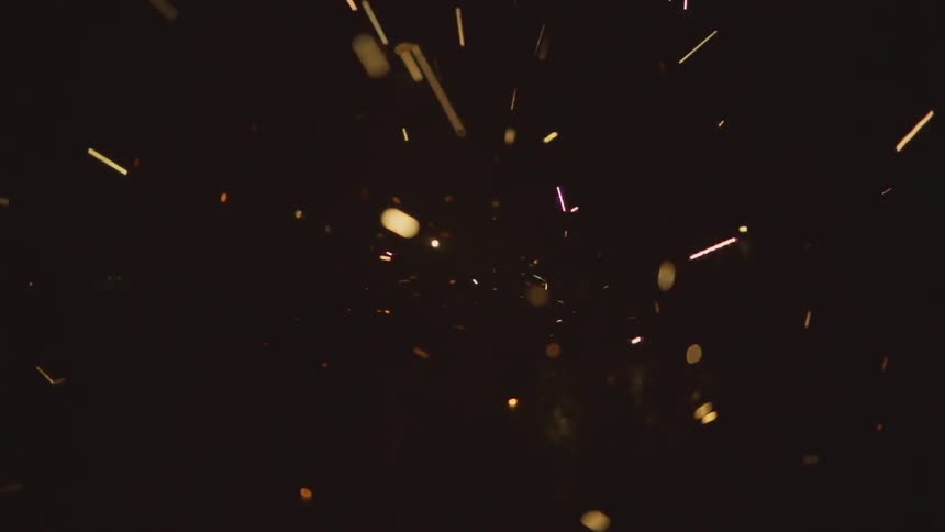Sparks popping and landing on a black floor