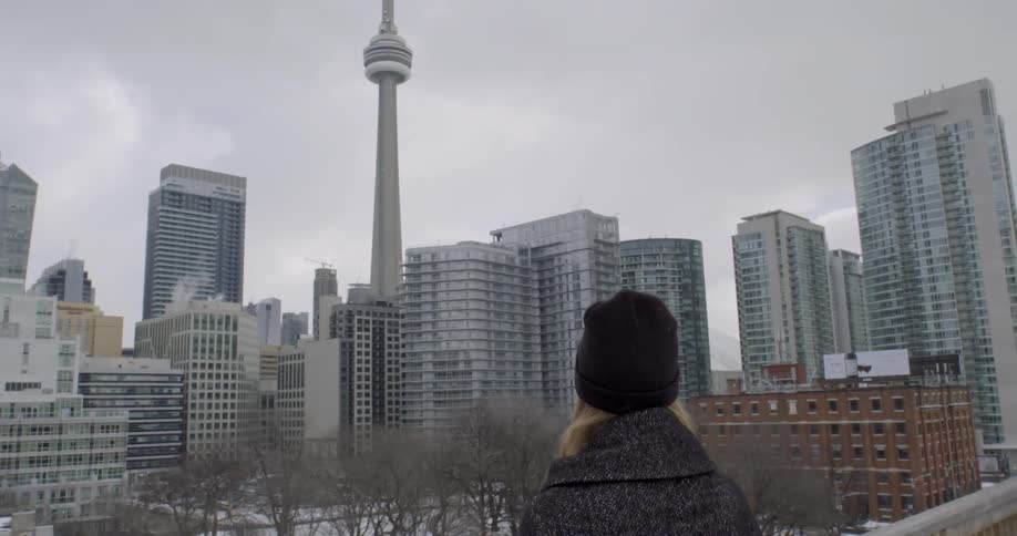 A woman looks at a city skyline on a cloudy winter day
