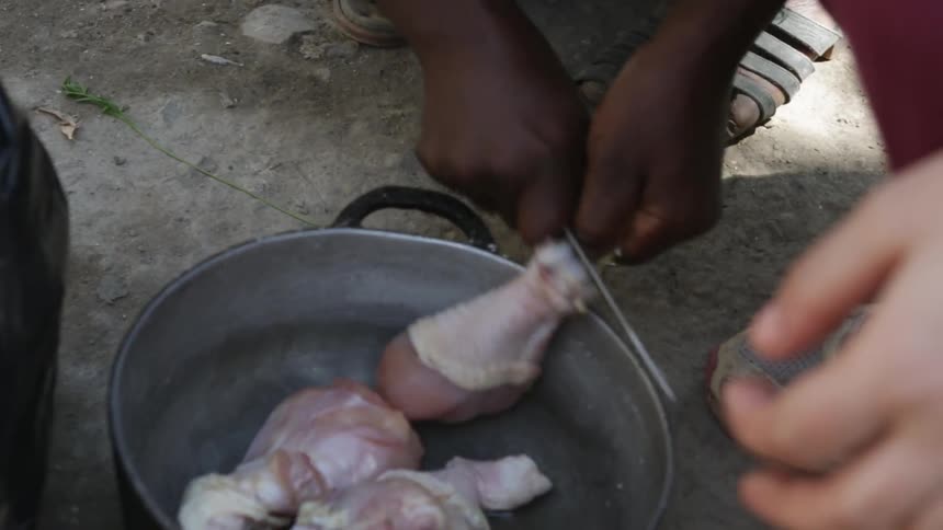 A person cuts fat from a chicken leg