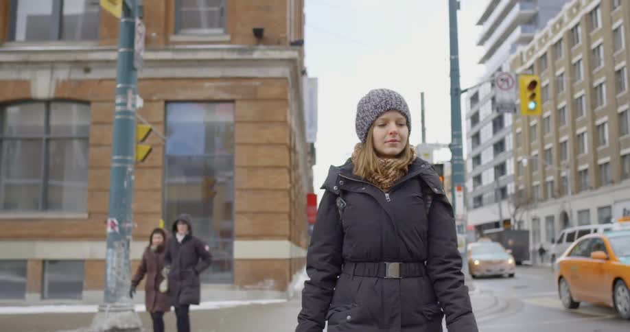A woman walks down a city sidewalk