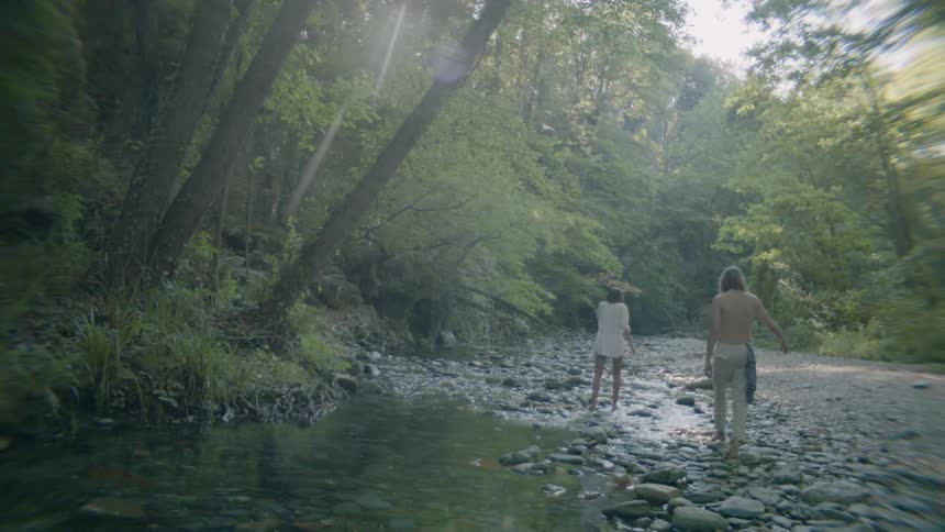 Three people walk on the rocks by the water