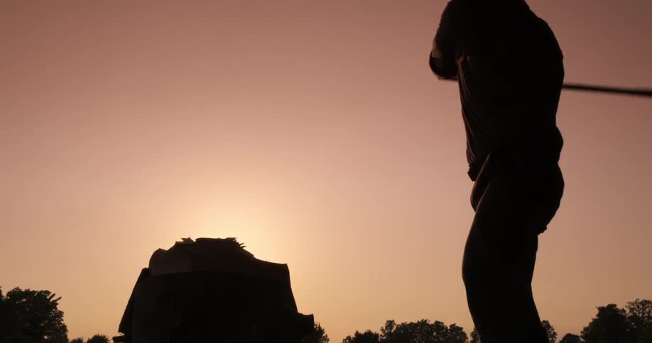 A man using an ax to destroy a book at sunset