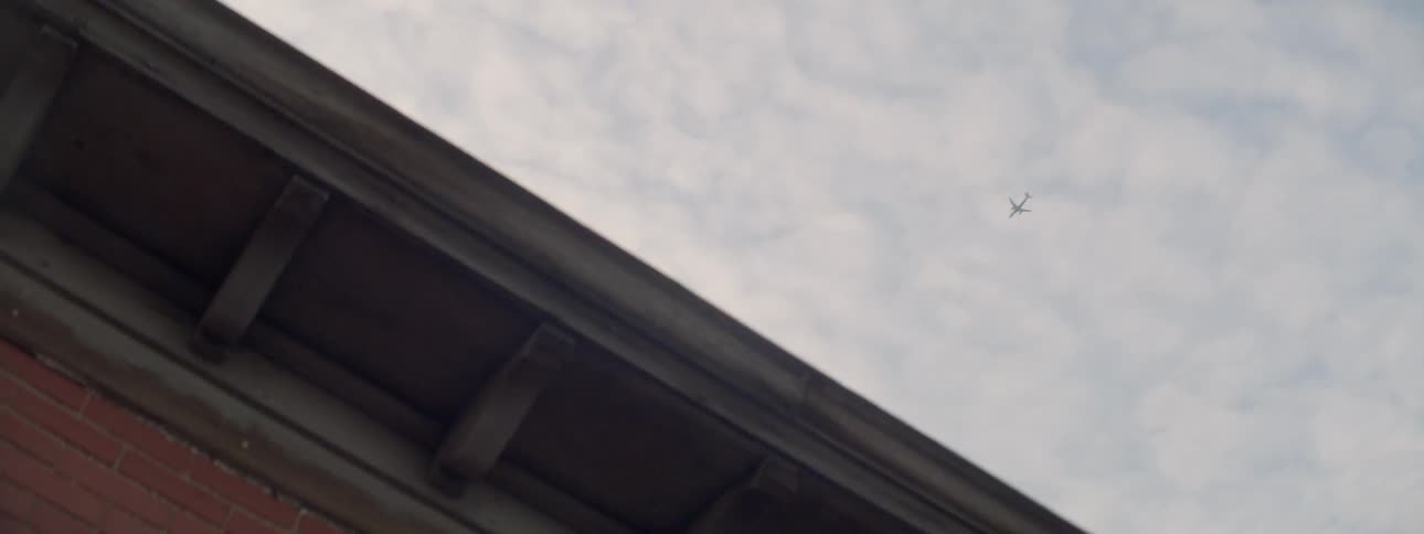 A plane is flying high over a building]