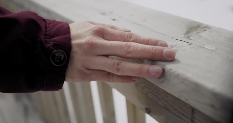 Man traces his hand across a wood barrier