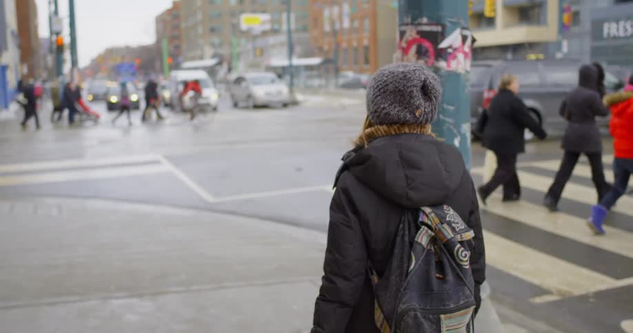A woman walks on a city sidewalk