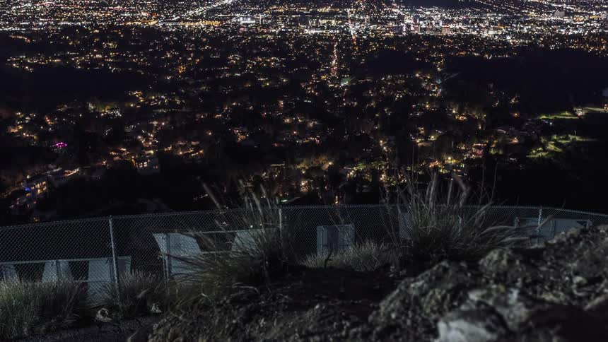 A hillside overlooks city lights and traffic at night