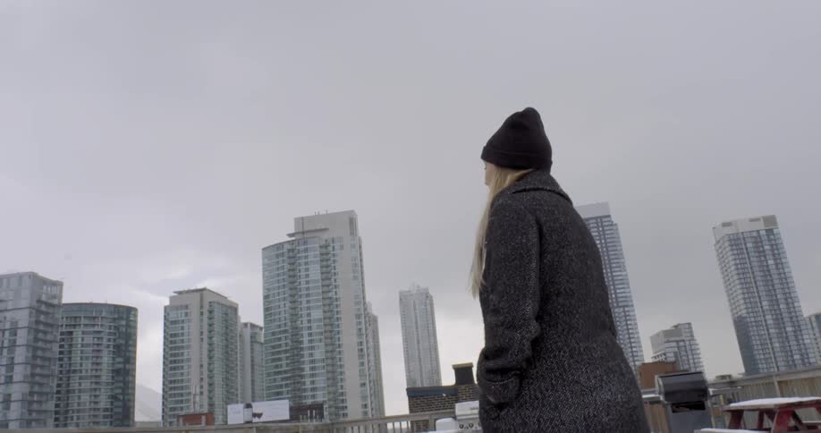 Woman walking outside near a city as it snows lightly