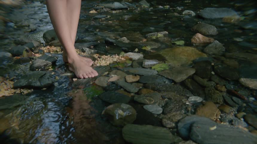 A woman stands on rocks in a stream