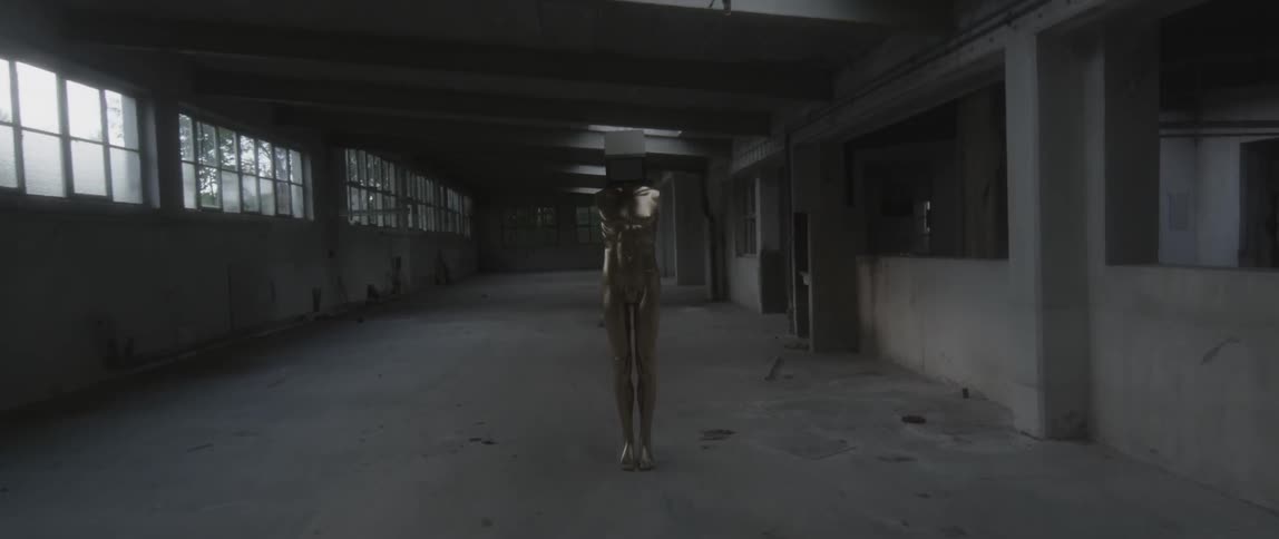 A mannequin has a television for a head in an empty warehouse