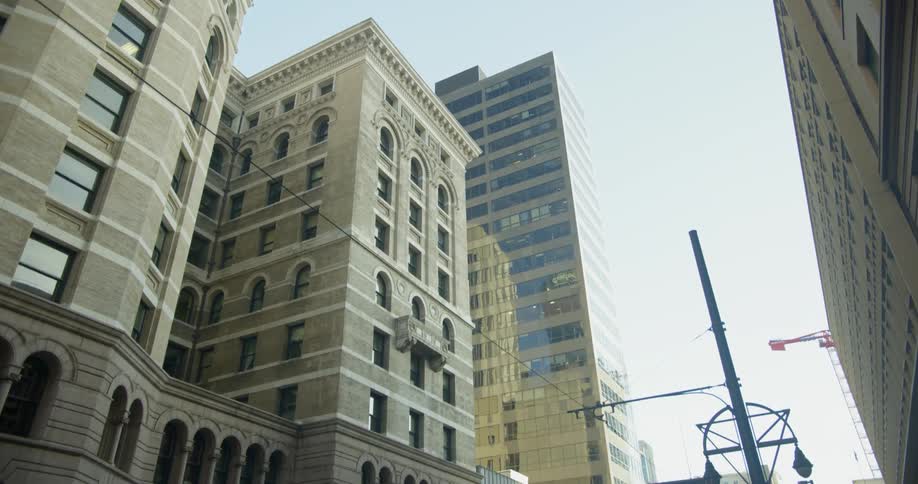 Cars sit parked on the street near the tall buildings