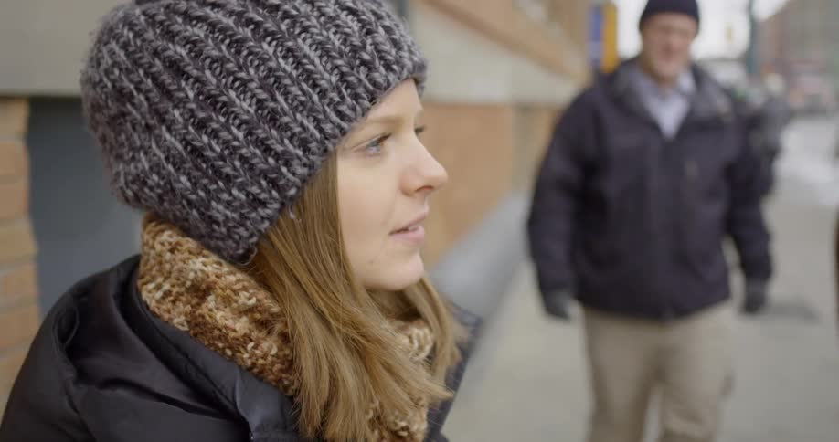 Woman looks around as people pass her on the sidewalk