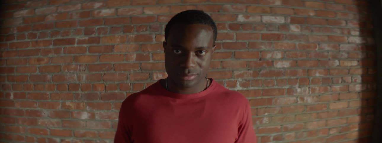 A man standing in front of a brick wall looks up