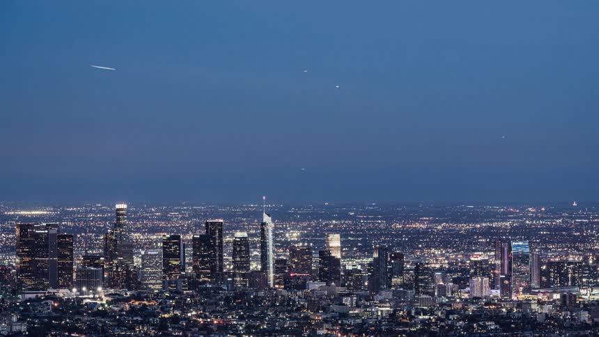 Planes fly through the sky as dusk is turning to night in a city