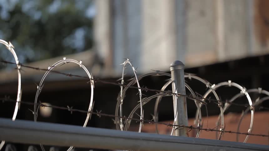 A barbed wire fence is protecting a property in daylight