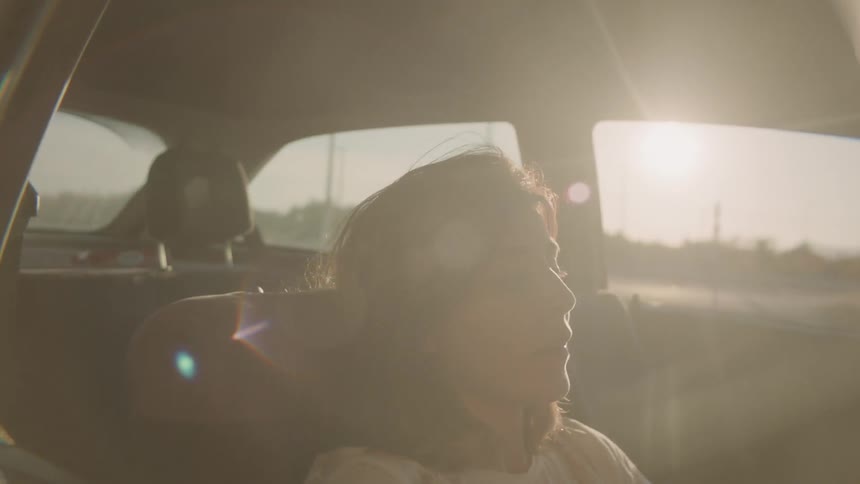 A woman sits in a parked car