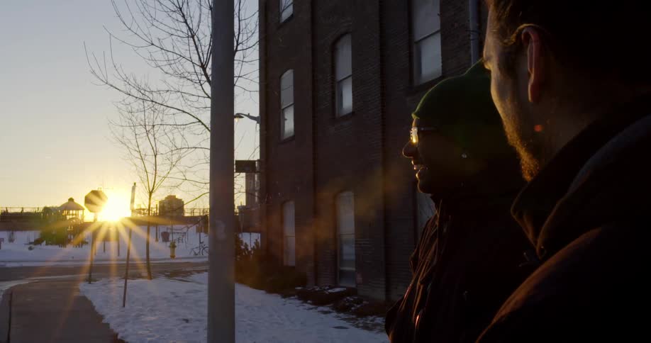 Two men standing outside a building at sunrise