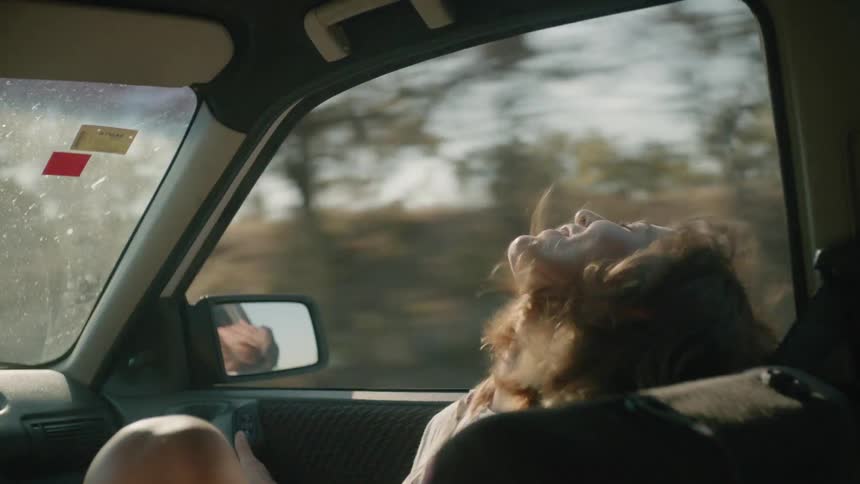 A woman rides in a car with the window down