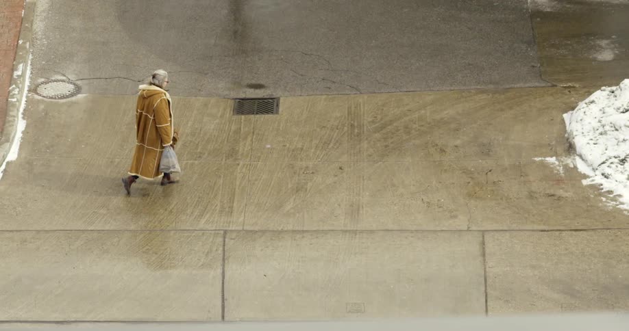 Woman carrying bags walking across a sidewalk