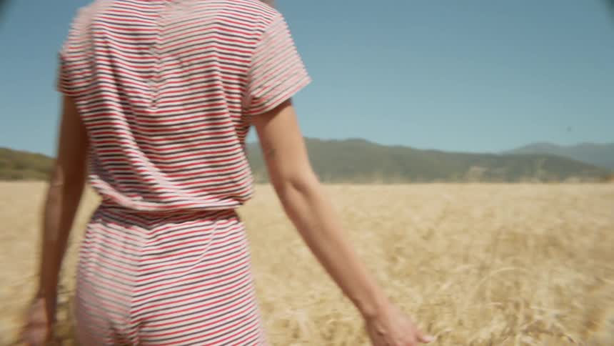 A woman is walking through the tall yellow grass