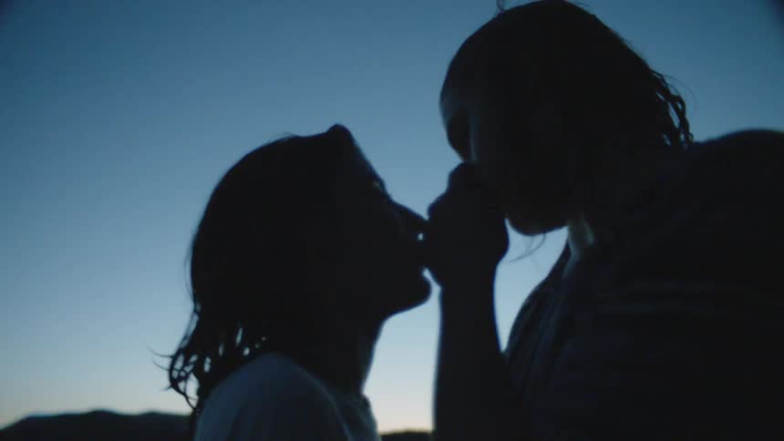 Man and woman kiss under a blue sky