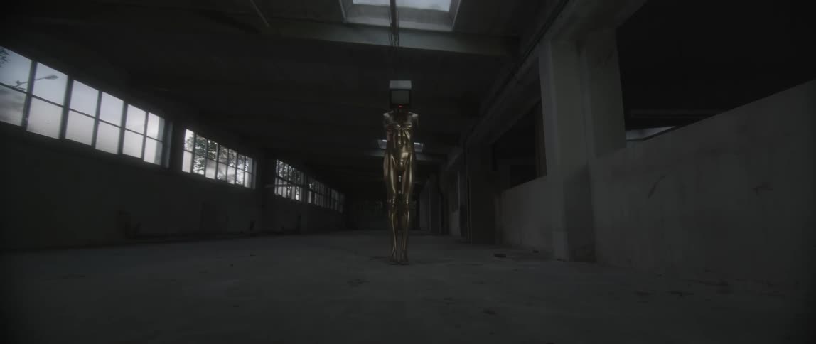 A mannequin has a television for a head in an empty warehouse
