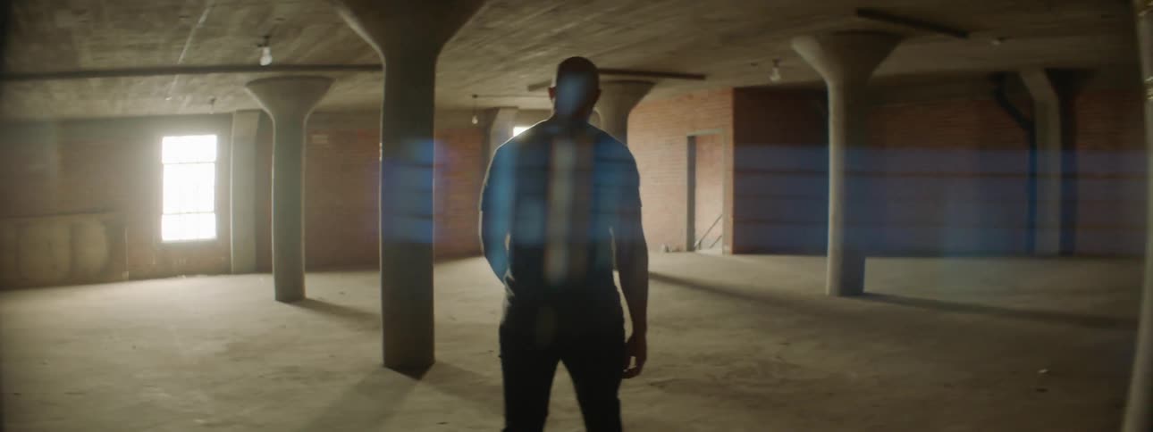 Man walks in an empty room towards sunny windows