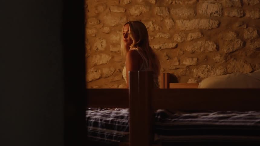 Man wearing a watch approaches a woman sitting on a bed