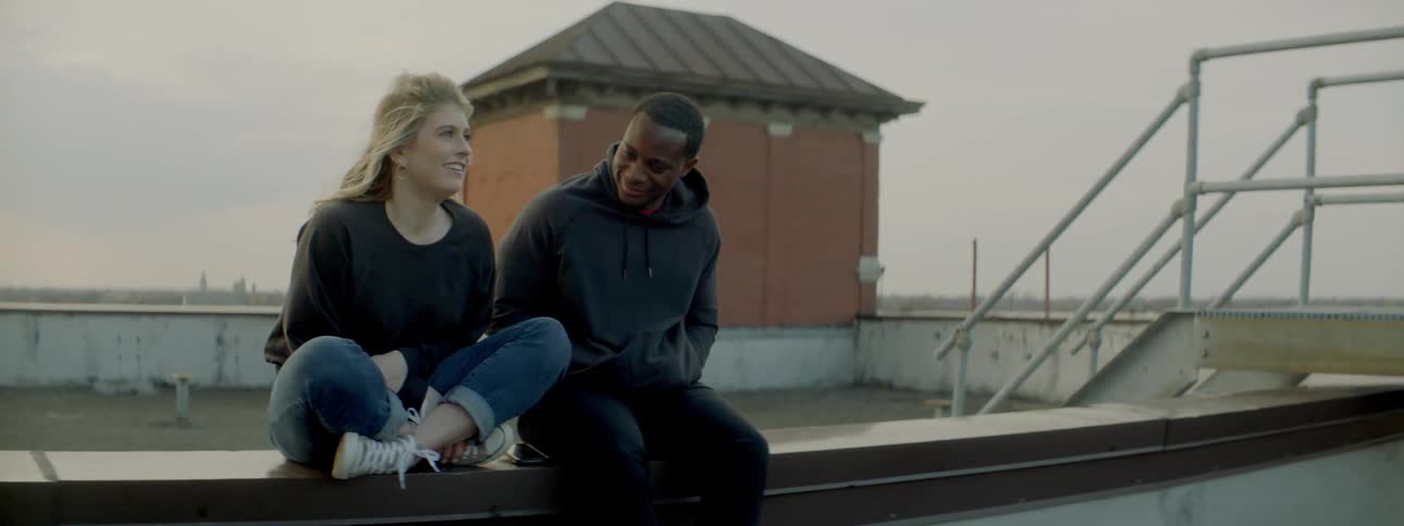 Man and woman talk on a building roof