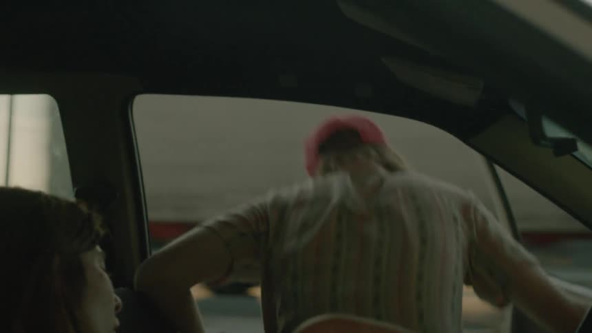 A man climbs out of a parked car at sunset
