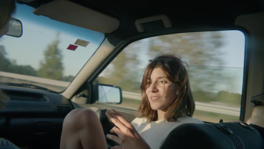 A woman smokes a cigarette while riding in a car
