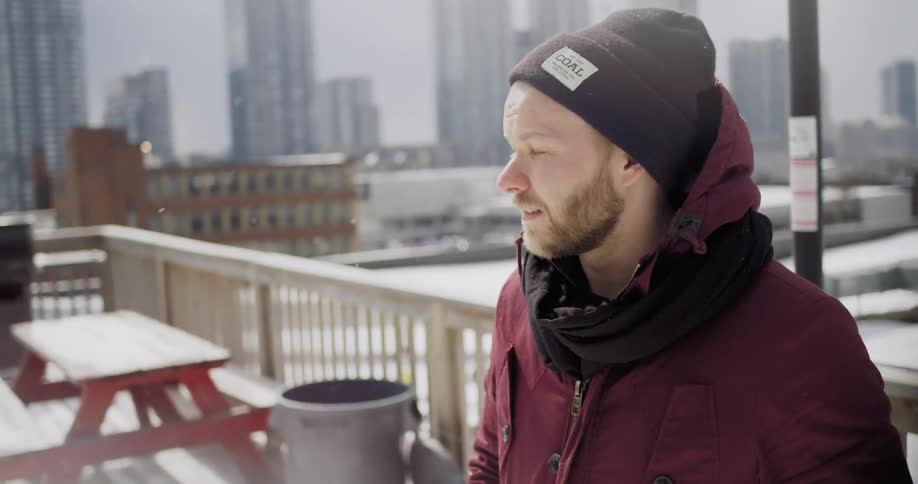 Man looks around a city as it lightly snows