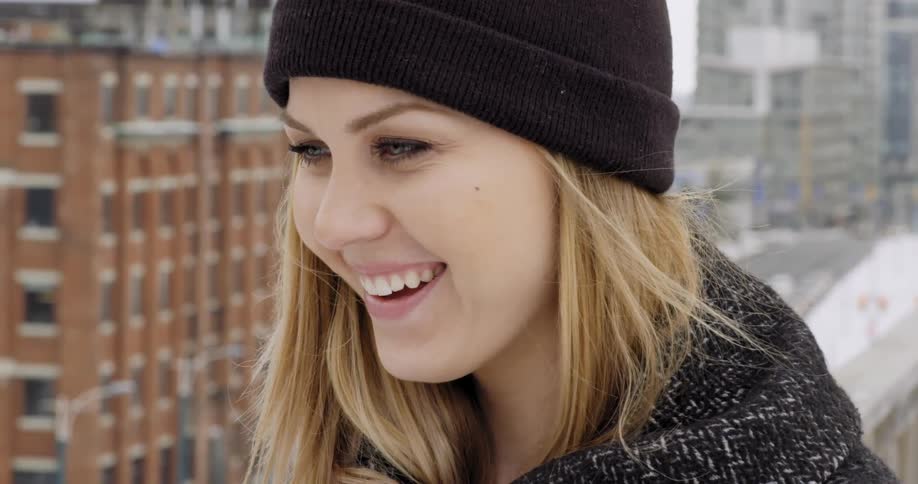A woman is smiling in a downtown city during winter
