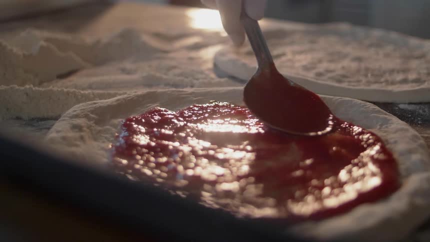 Pizza sauce is spread on dough