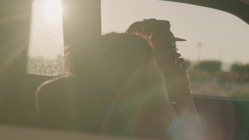 A girl is taking the sunglasses of a boy's face as they ride in a car in daylight