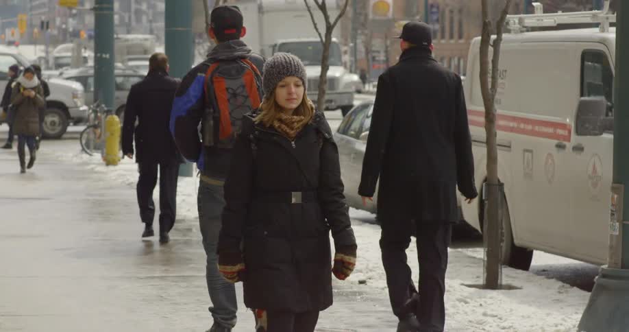 People are walking down a busy city street while its snowing
