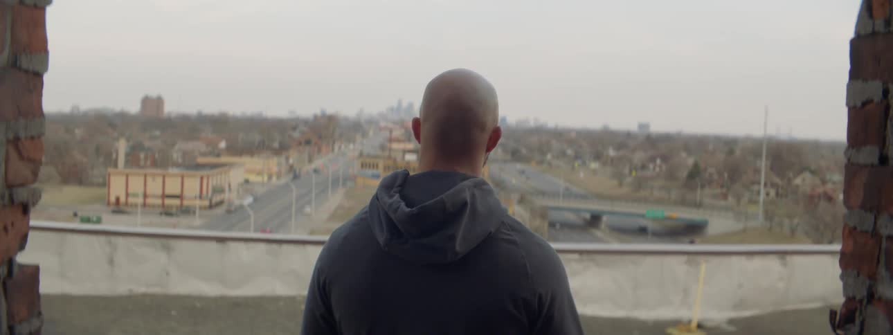 A man stands on the roof overlooking the city