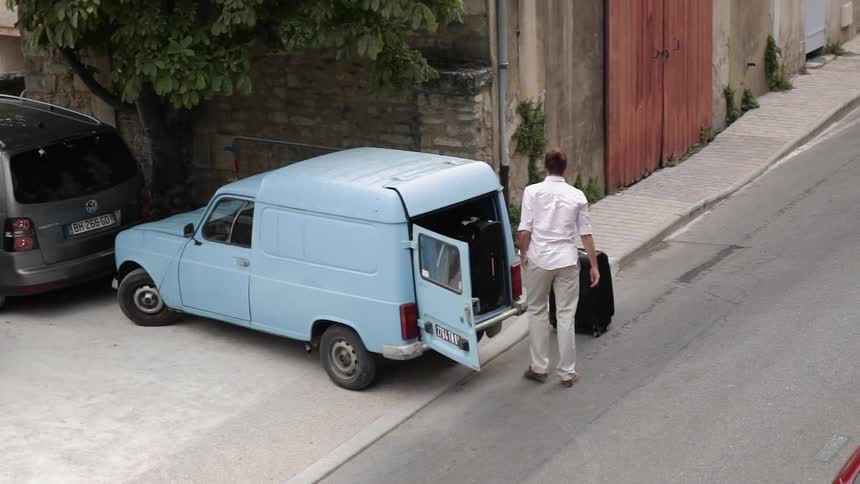 A man is loading luggage in the vehicle