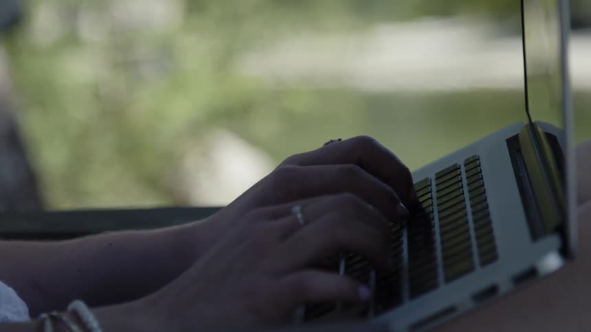 Woman wearing rings types on a laptop keyboard
