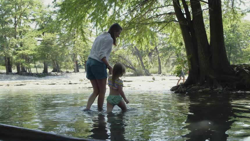 Woman and girl wade in a lake