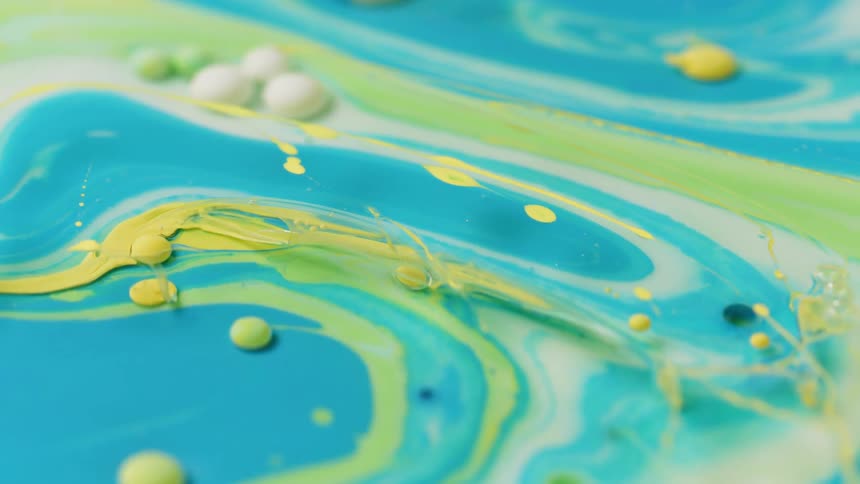 Yellow, blue, green and white liquid swirl together