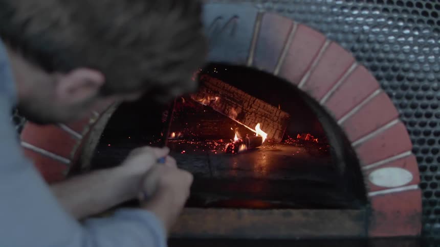 Person stokes a fireplace with a poker