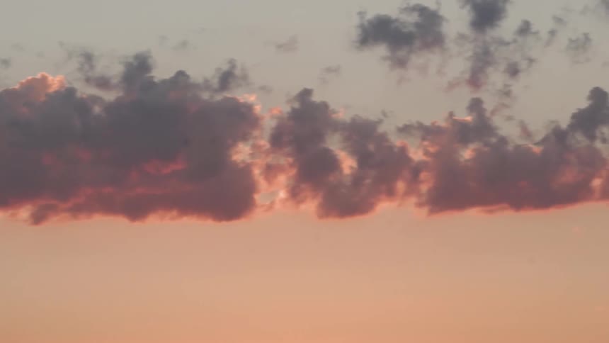 The sun is setting as a row of clouds reflect the light