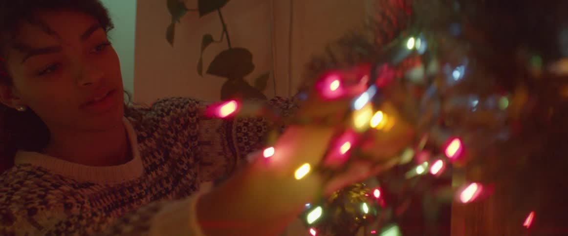 A woman hangs christmas lights indoors