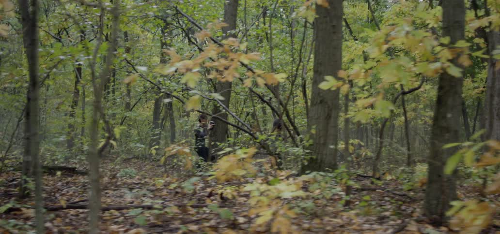 A man and woman run in a forest