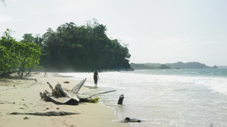 A woman walks along the tide on the beach on a cloudy day