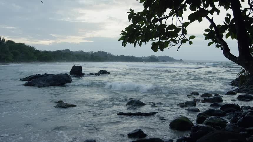 The waves splash against the rocks near the shore