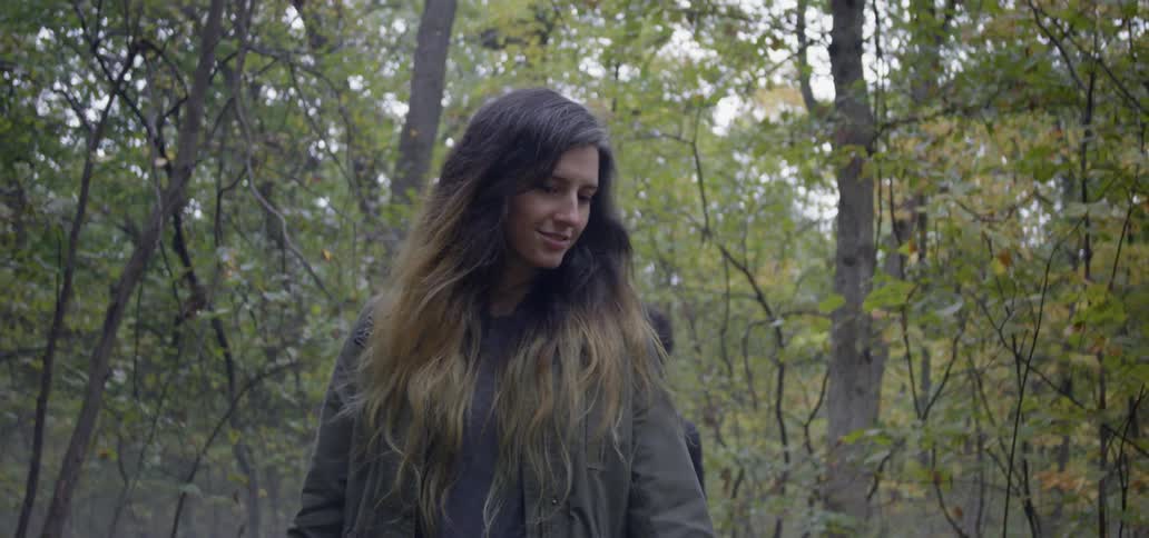 The two people smile as they hike in the woods