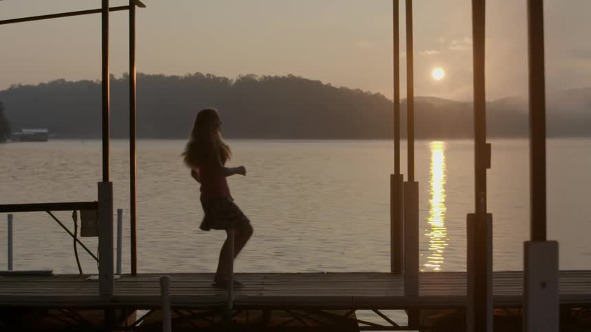 Woman running across a boardwalk to watch the sunset