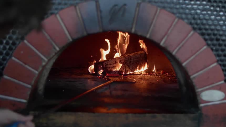 Someone is adding wood to a wood burning oven