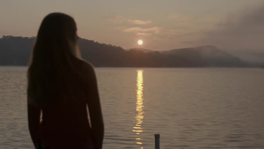 Girl standing on a dock looking at a lake